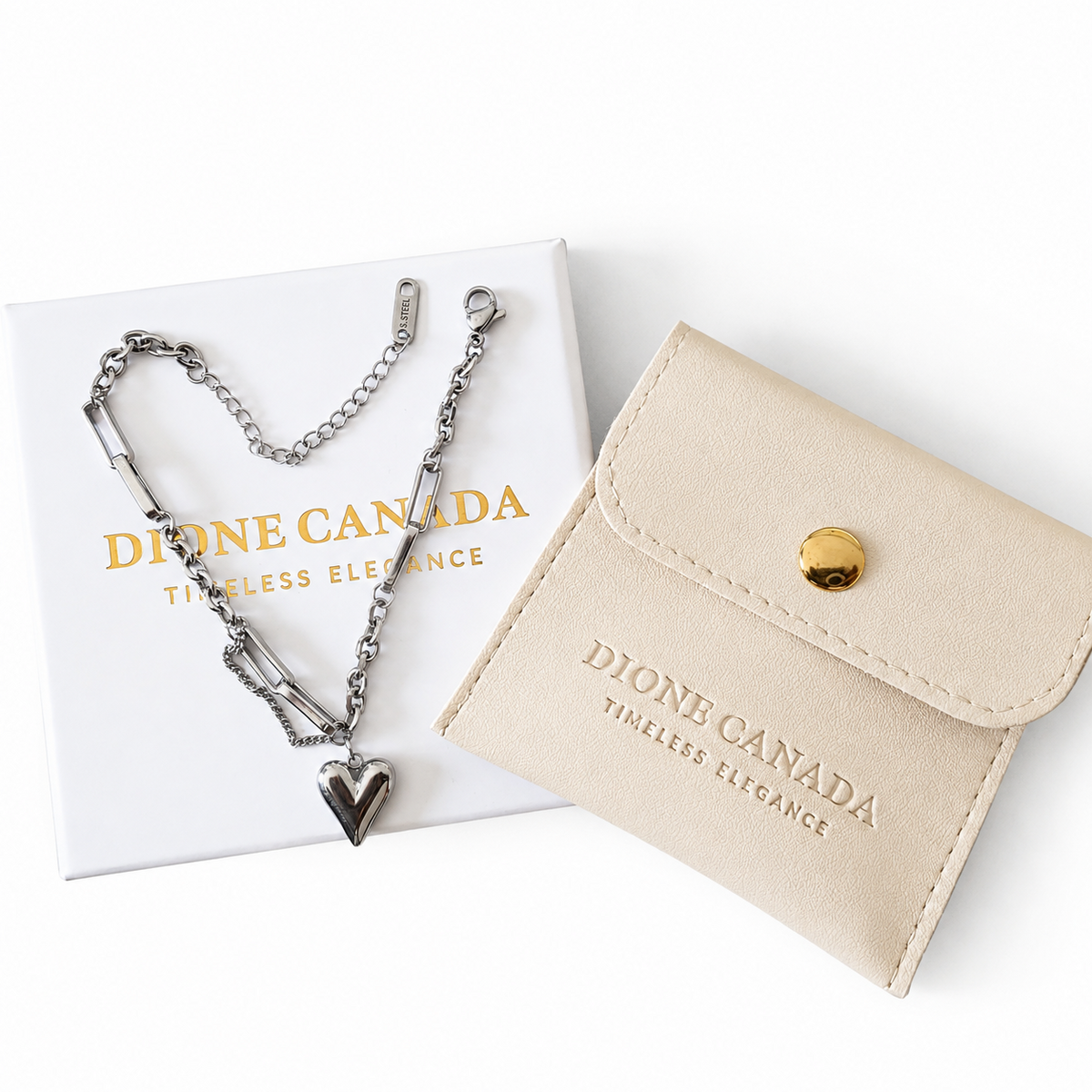 A silver chain necklace with a heart-shaped pendant and adjustable links, displayed with its white presentation box and a beige leatherette wallet featuring gold-toned branding.