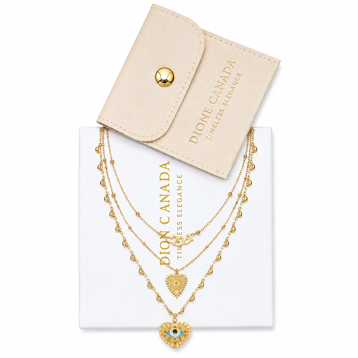 Dione Canada layered gold necklace featuring heart and evil eye pendants on a white jewelry box with luxury jewelry pouch on a white background.