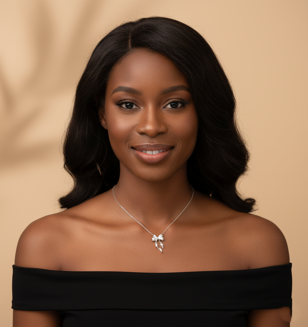 Woman wearing a black off-shoulder top and a necklace with a bow pendant against a beige background