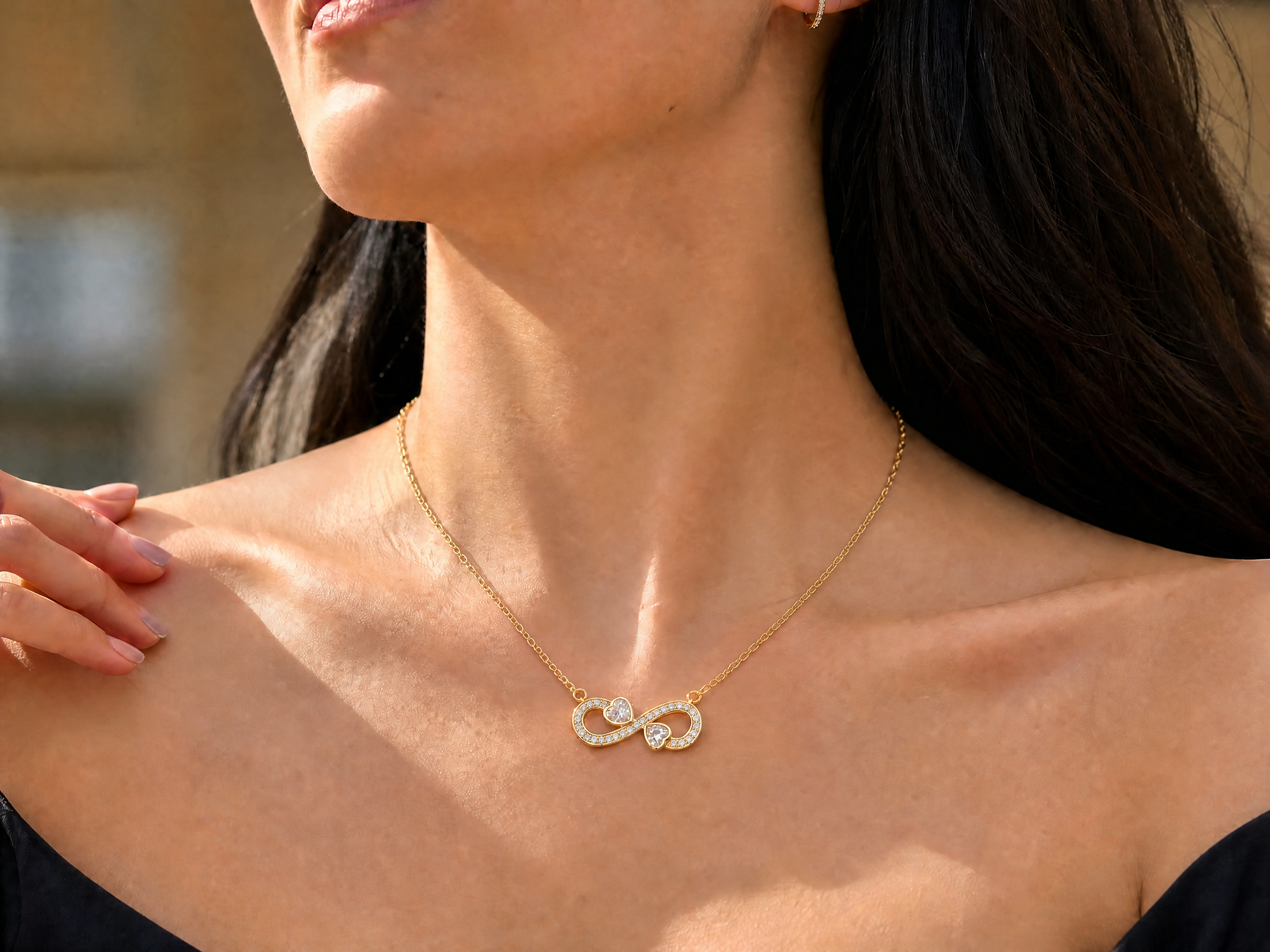 Woman wearing the Elara Necklace, a gold infinity heart pendant necklace with zircon stones