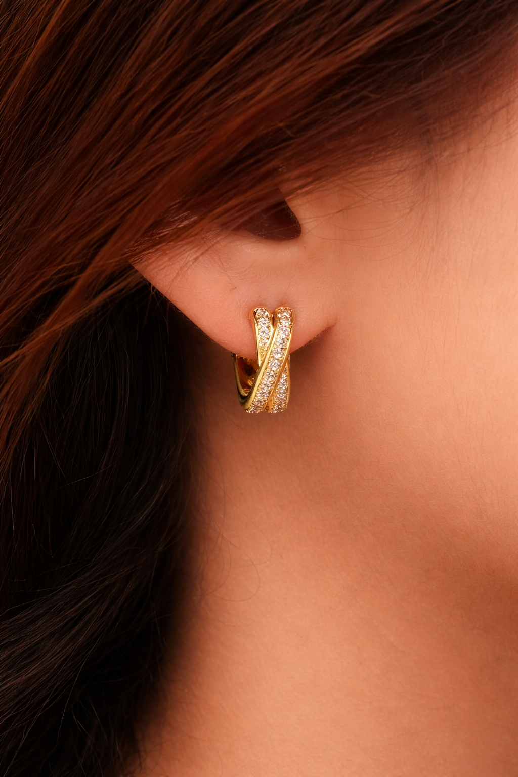 Gold crisscross hoop earrings with diamond accents worn on ear, elegant minimalist jewelry for women