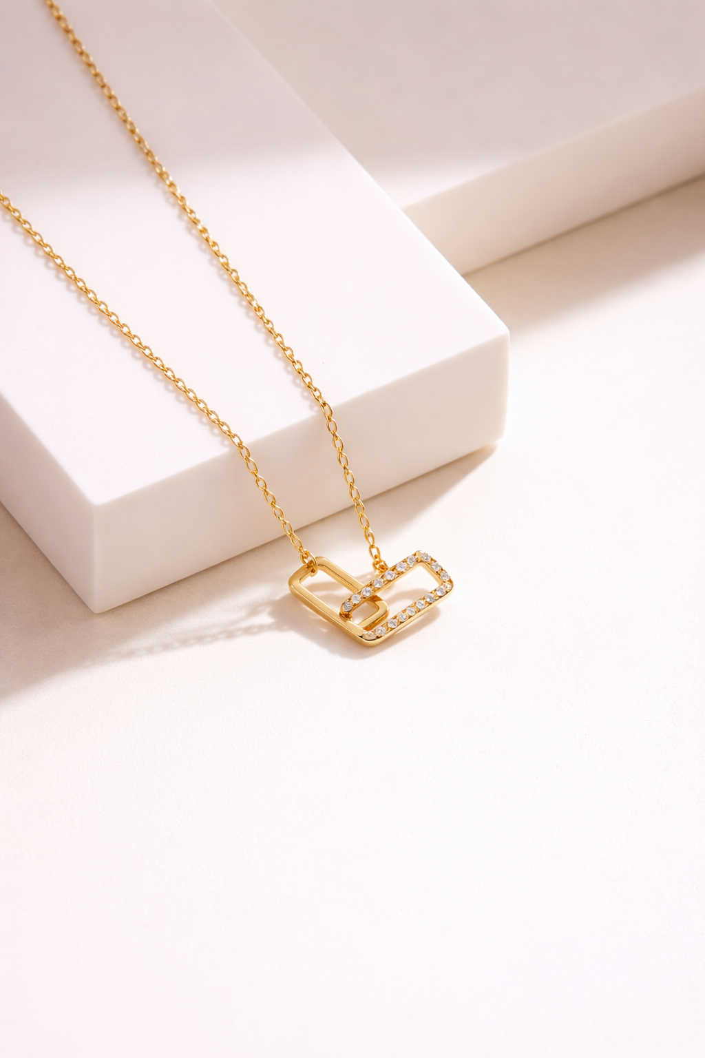 Gold double rectangle pendant necklace with diamond accents on white background, modern geometric jewelry