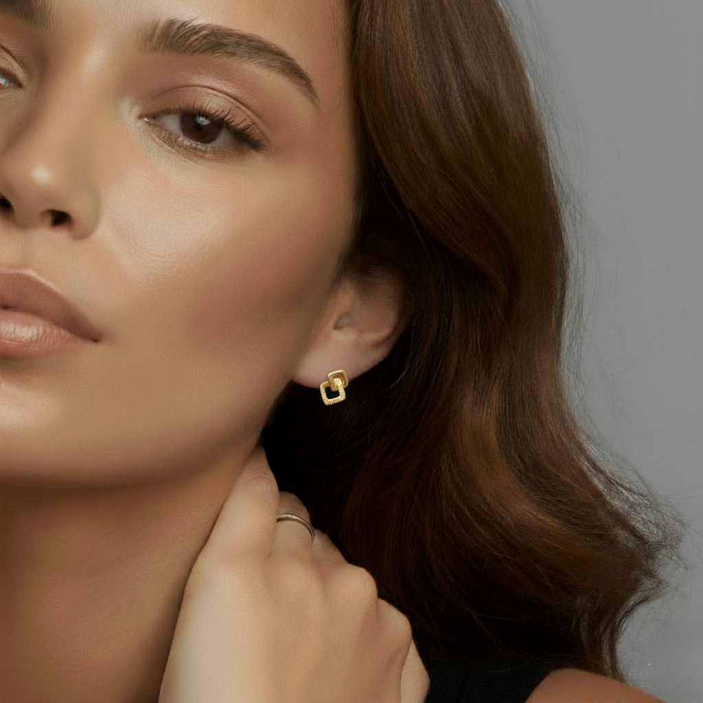 Close-up of a woman wearing gold geometric stud earrings and a minimal gold ring