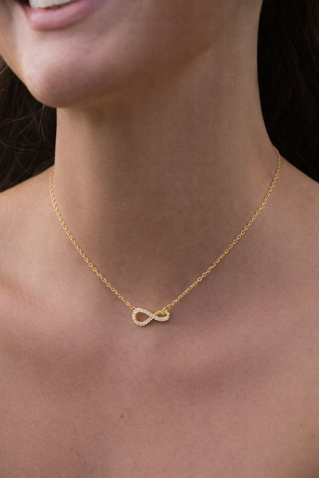 Gold infinity pendant necklace with diamond accents worn on model, minimalist elegant jewelry for women