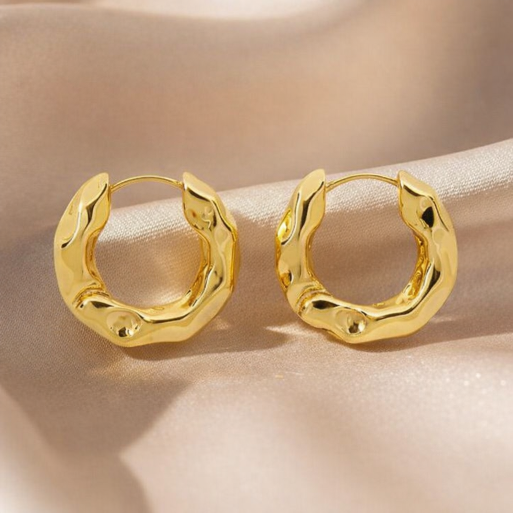 Gold hoop earrings on a beige surface