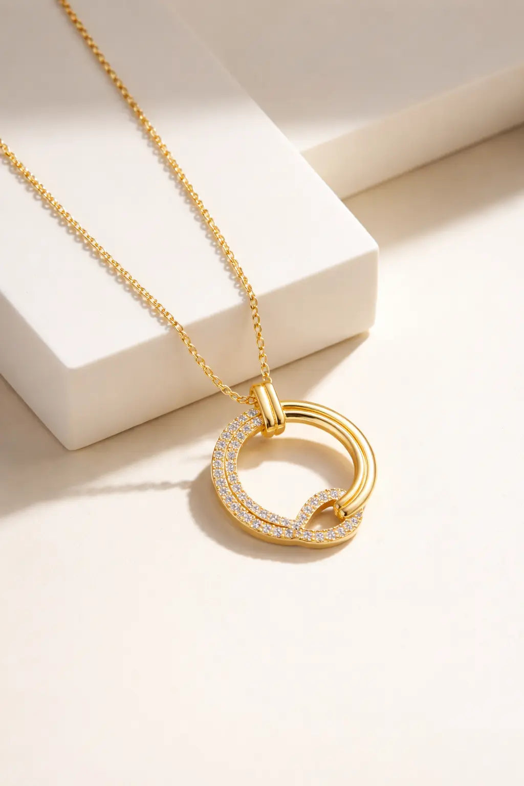 Gold layered circle pendant necklace with diamond accents on neutral background, modern elegant jewelry design