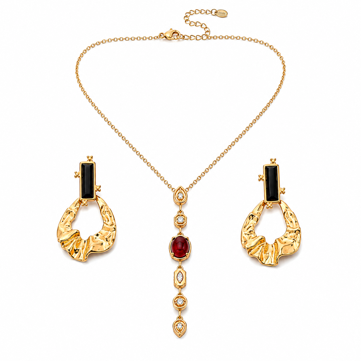 Gold jewelry set featuring a necklace and matching earrings with black rectangular stones, a central red oval stone, and clear teardrop-shaped stones on a white background.