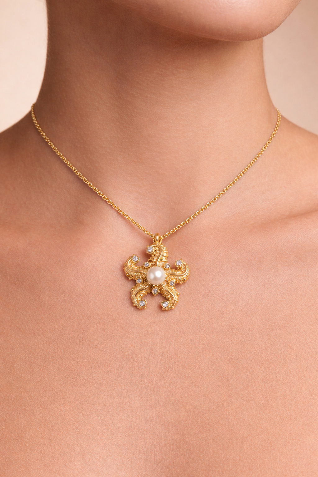 Woman wearing a gold octopus pendant necklace with pearl center and crystal accents in a vintage-inspired design