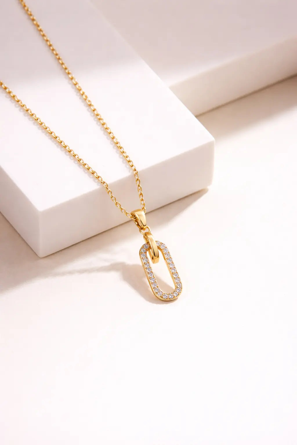 Gold paperclip link pendant necklace with diamond accents on neutral background, modern minimalist jewelry