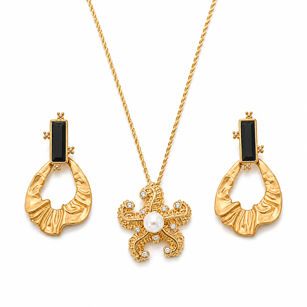 Gold jewelry set featuring a necklace with a pearl and crystal pendant and matching drop earrings with black rectangular stones and textured gold crescent-shaped pendants, on a white background.