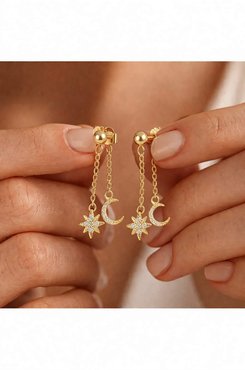Gold star and moon dangle earrings with diamond accents held in hand, celestial minimalist jewelry for women