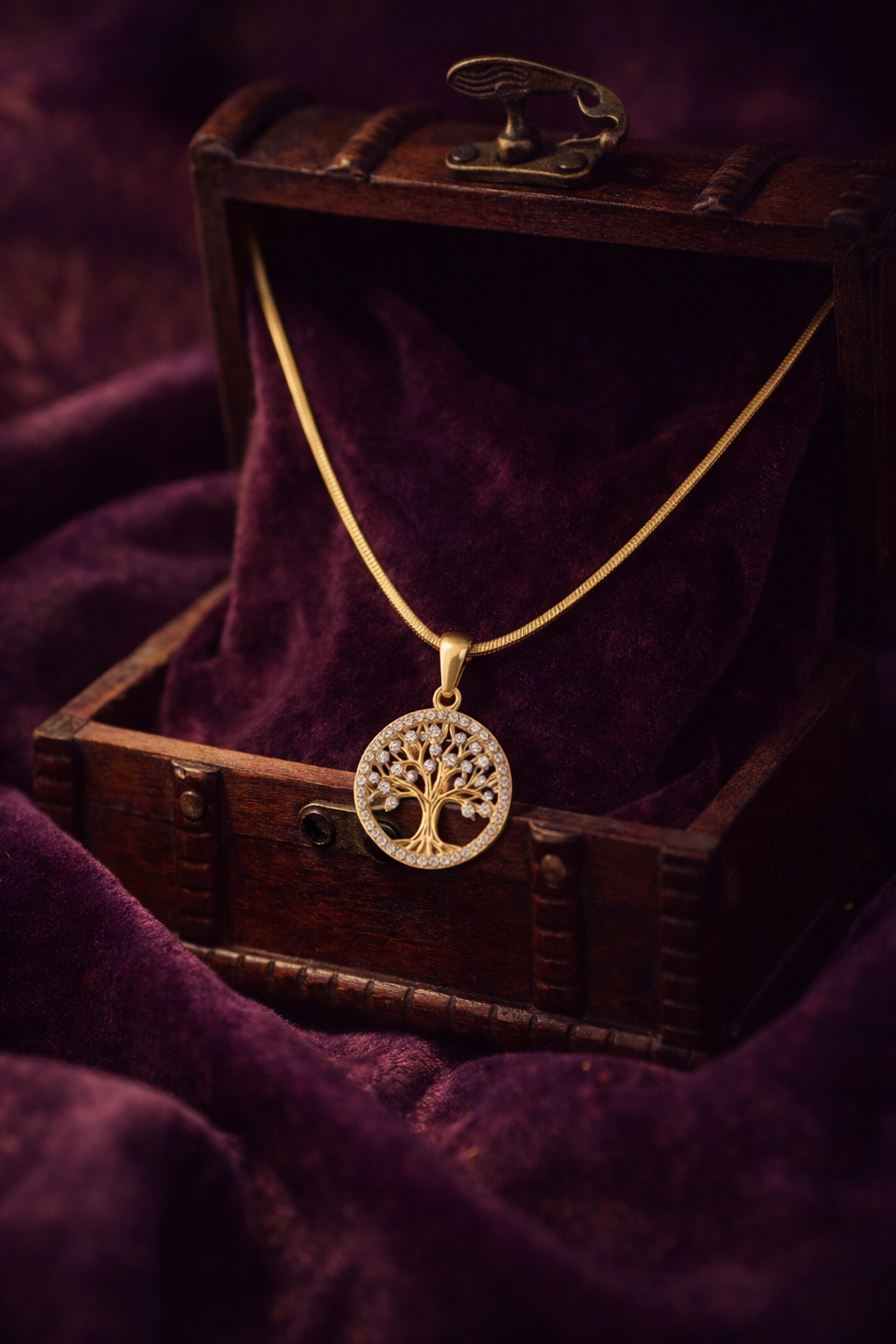 Gold necklace with a tree of life pendant on a dark purple fabric background