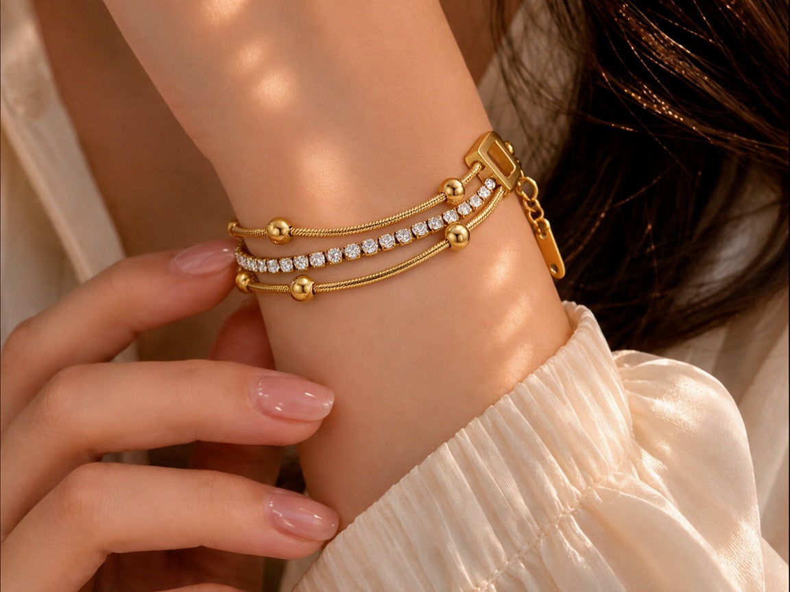 Woman wearing the Lumora Bracelet, a layered gold tennis chain bracelet with rhinestone detail