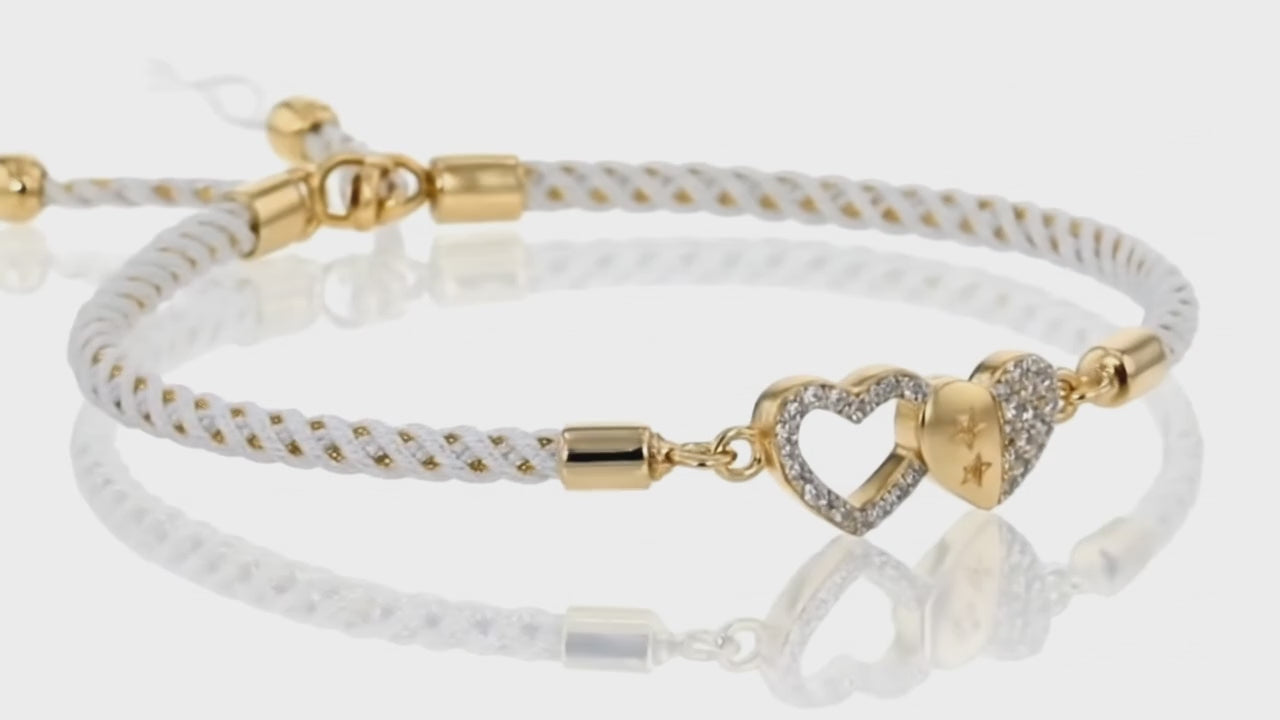 Gold heart charm braided bracelet by Dione Canada with pavé crystal detailing and adjustable cord design, luxury studio close-up.