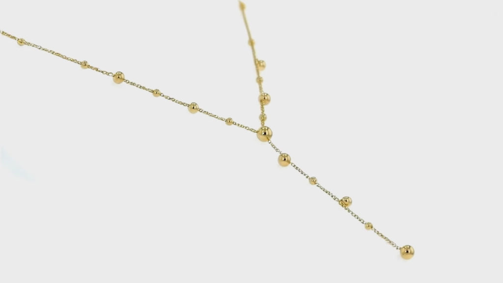 Gold beaded layered necklace by Dione Canada featuring delicate chain accents and polished bead detailing, luxury studio close-up.