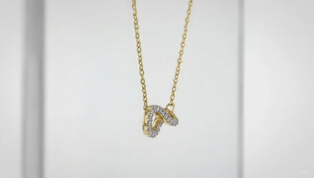 Gold crystal twist pendant necklace by Dione Canada featuring a curved sparkling design on a delicate chain, shown in a clean luxury studio close-up.