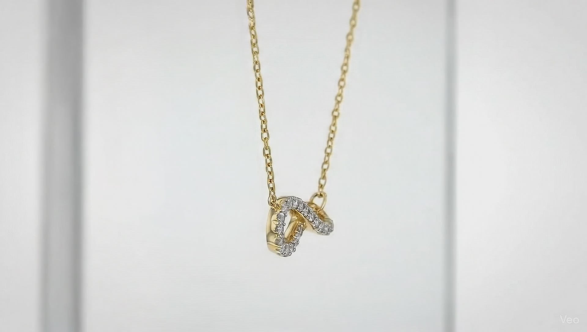 Gold crystal twist pendant necklace by Dione Canada featuring a curved sparkling design on a delicate chain, shown in a clean luxury studio close-up.