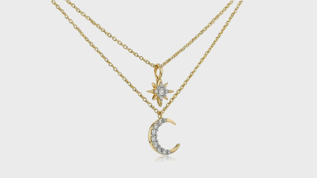 Gold layered necklace by Dione Canada featuring a crystal-accent moon pendant and a delicate star charm on dual chains, luxury studio close-up.