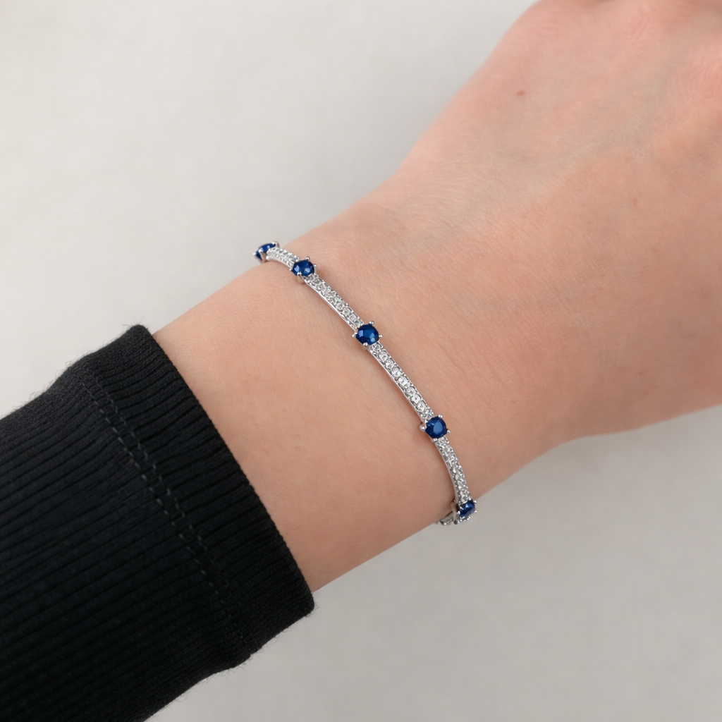 Sterling silver tennis bracelet with blue stones and diamond accents worn on wrist, elegant fine jewelry for women