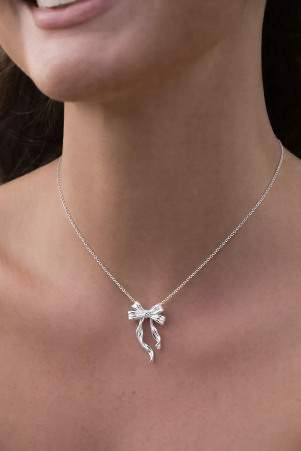 Sterling silver bow pendant necklace worn on model, minimalist elegant jewelry for women