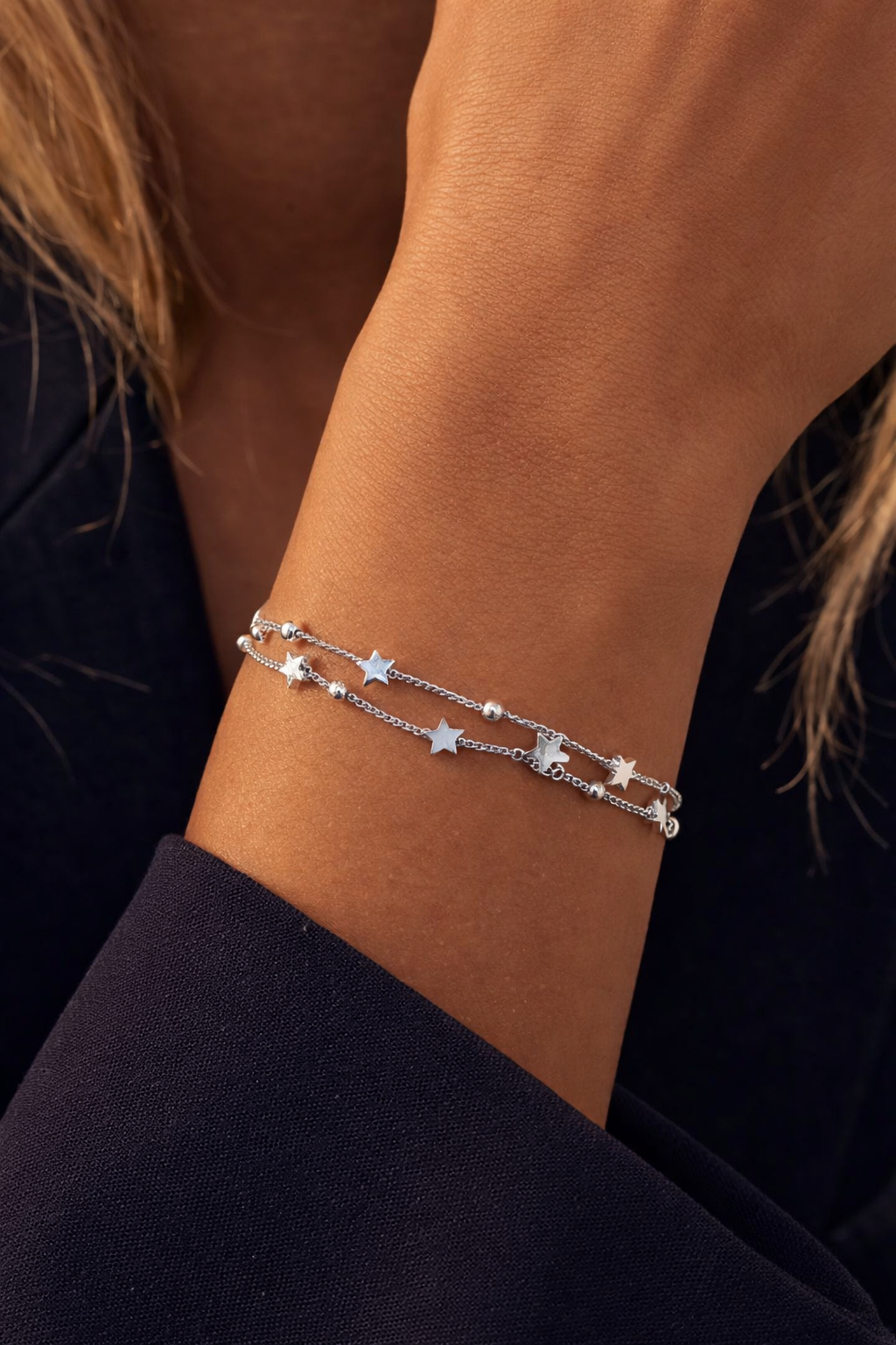 Sterling silver double chain bracelet with star charms worn on wrist, minimalist layered jewelry for women