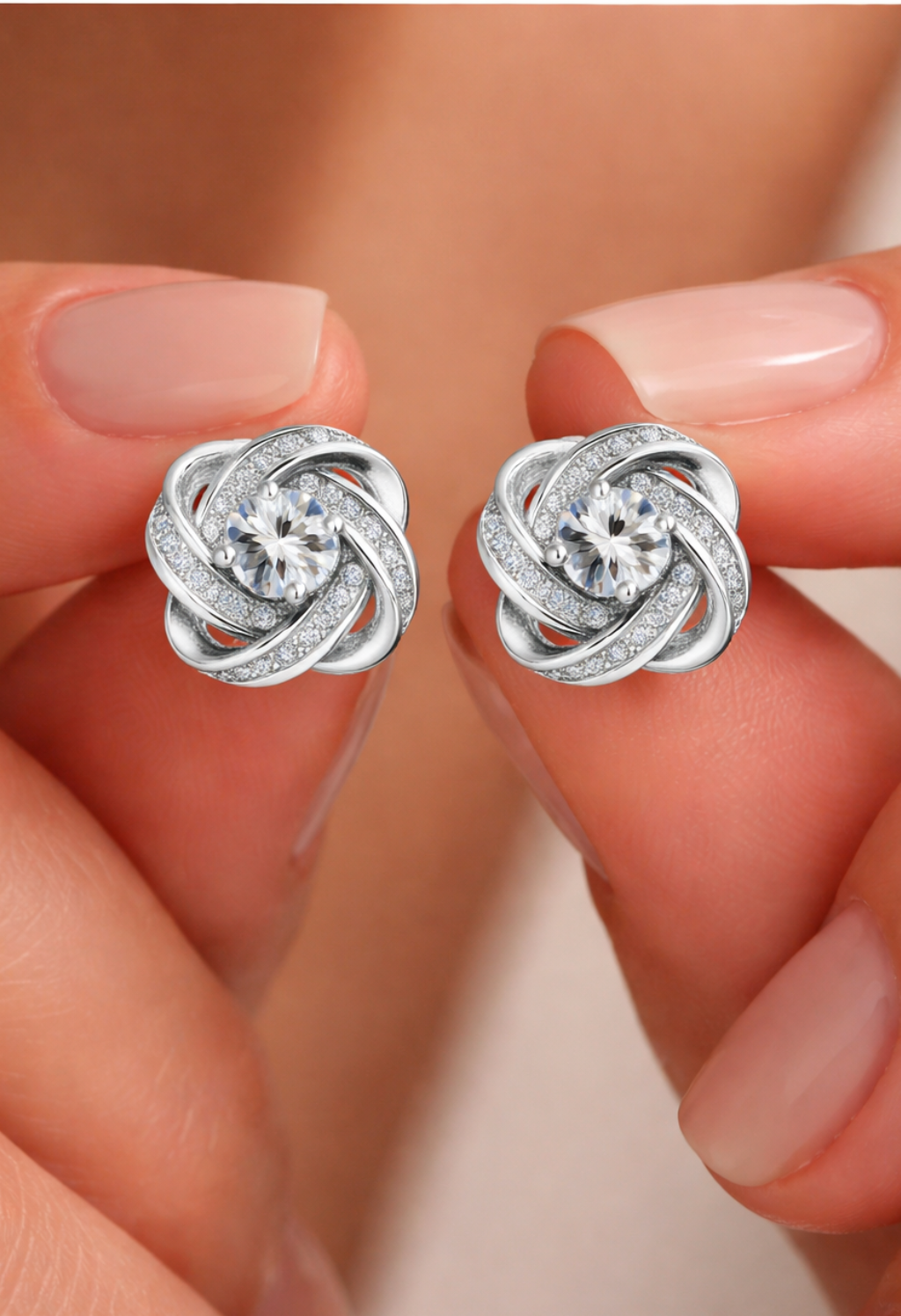 Sterling silver infinity knot stud earrings with central diamond held in hand, elegant minimalist jewelry for women